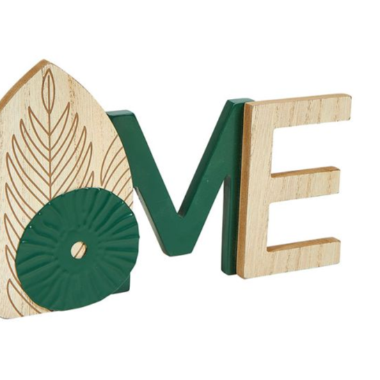 Mot déco "Home" en bois vert et naturel posé dans un salon accueillant et chaleureux